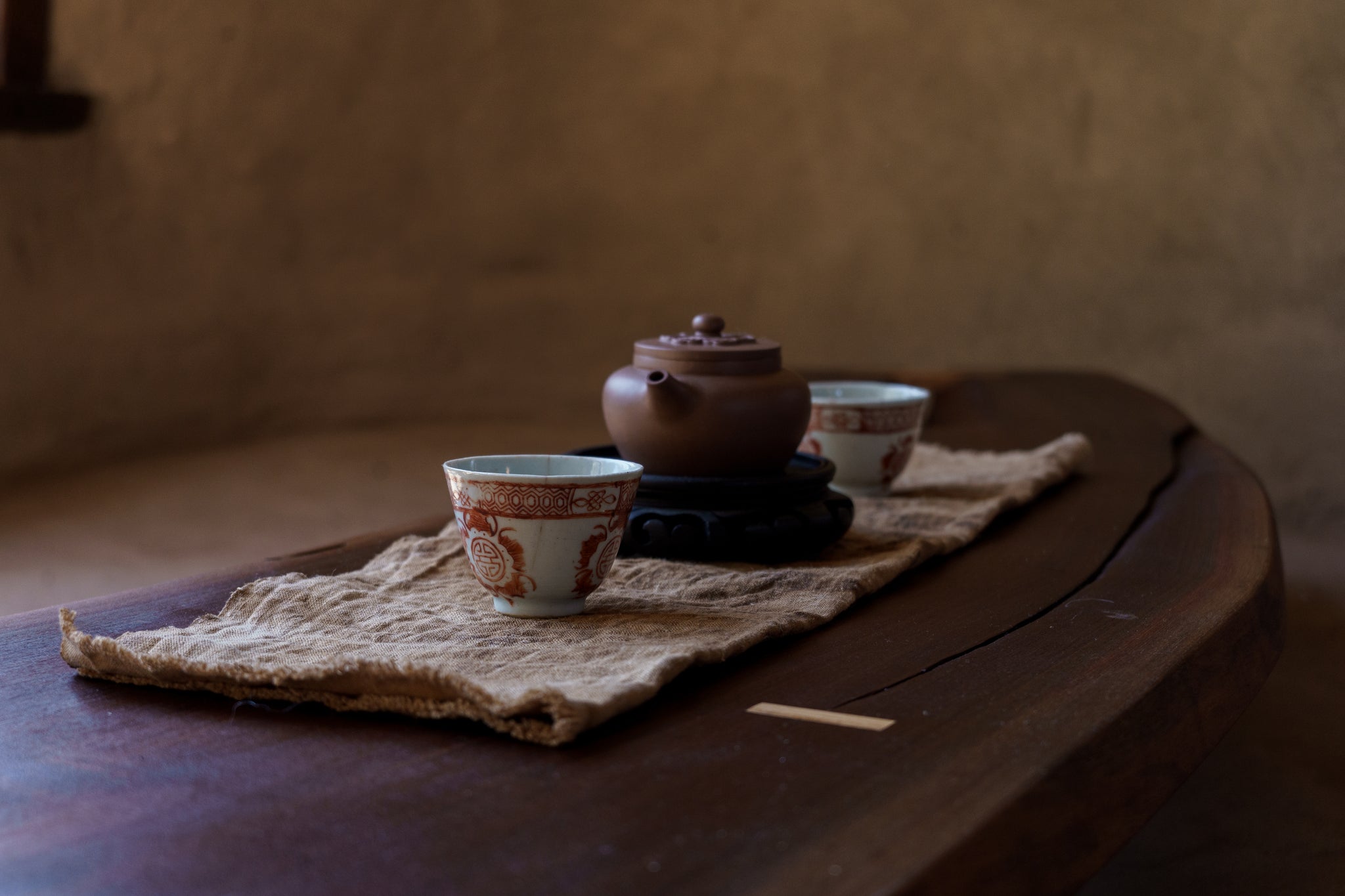 Tea set with a teapot and cups on a wooden table with a textured background