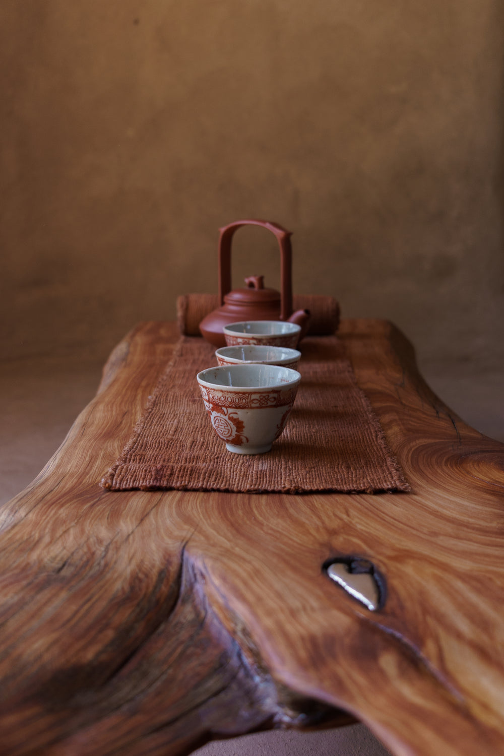 Tea set with a teapot and cups on a wooden surface with a textured background