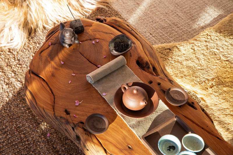 Wooden surface with decorative items including a teapot and cups on a textured surface.